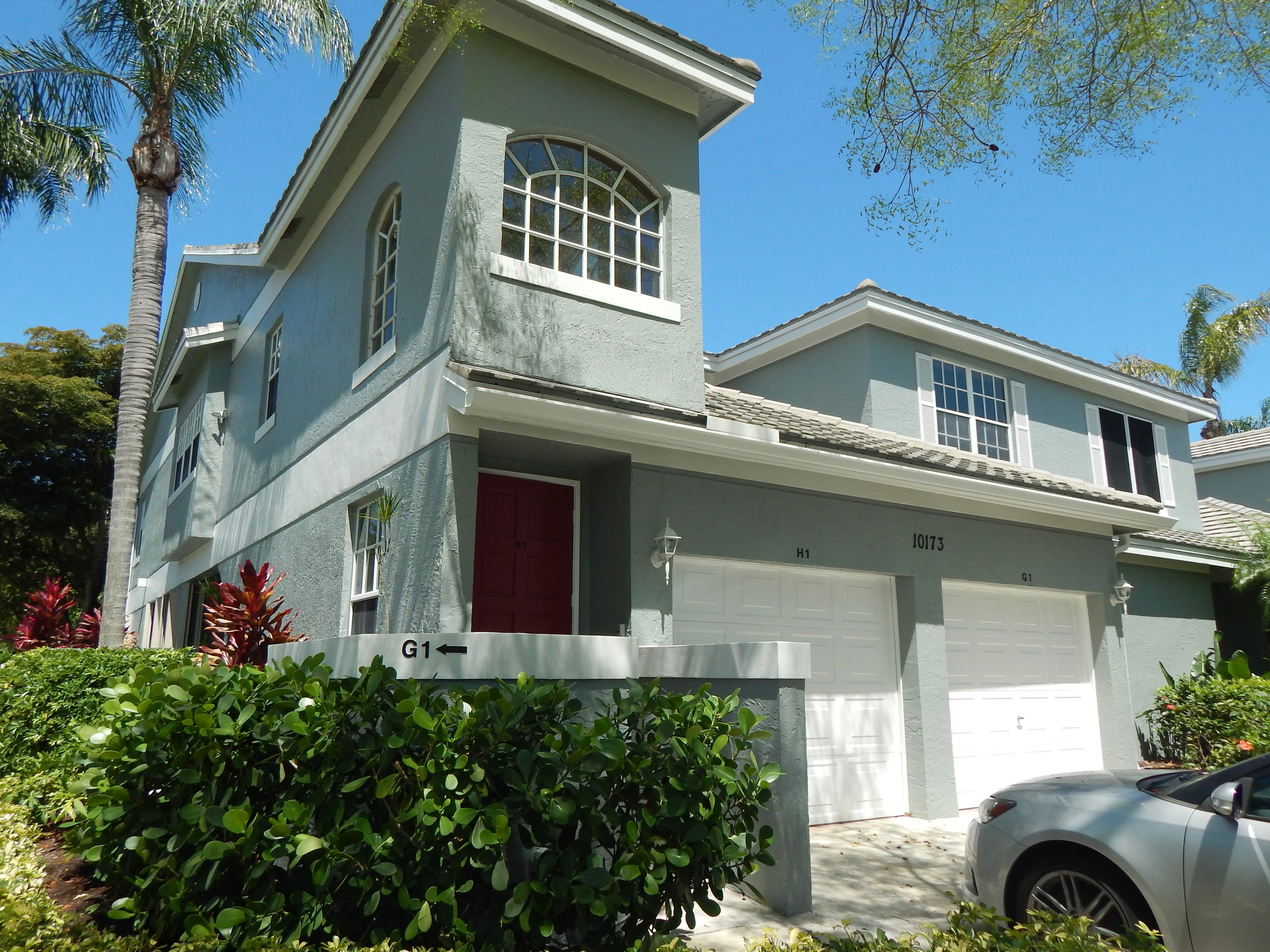 Blue-grey two-story townhome with palm trees and tropical landscaping